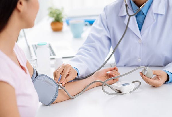 Doctor checking blood pressure of the patient, selective focus